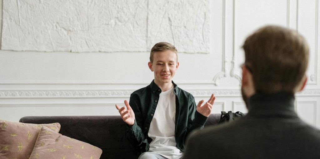 Man in Black Suit Jacket Sitting on Brown Wooden Chair
